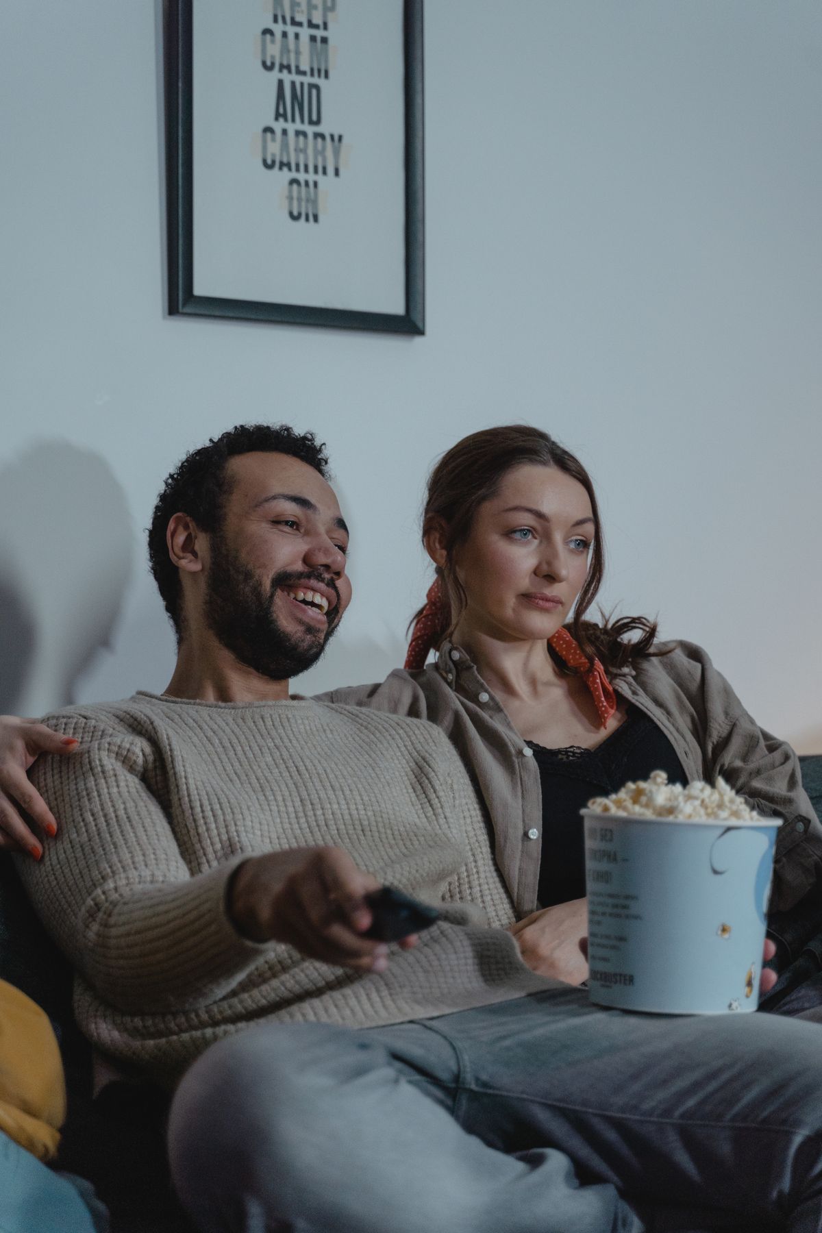 Couple on a sofa watching a film at home with a bucket of popcorn
